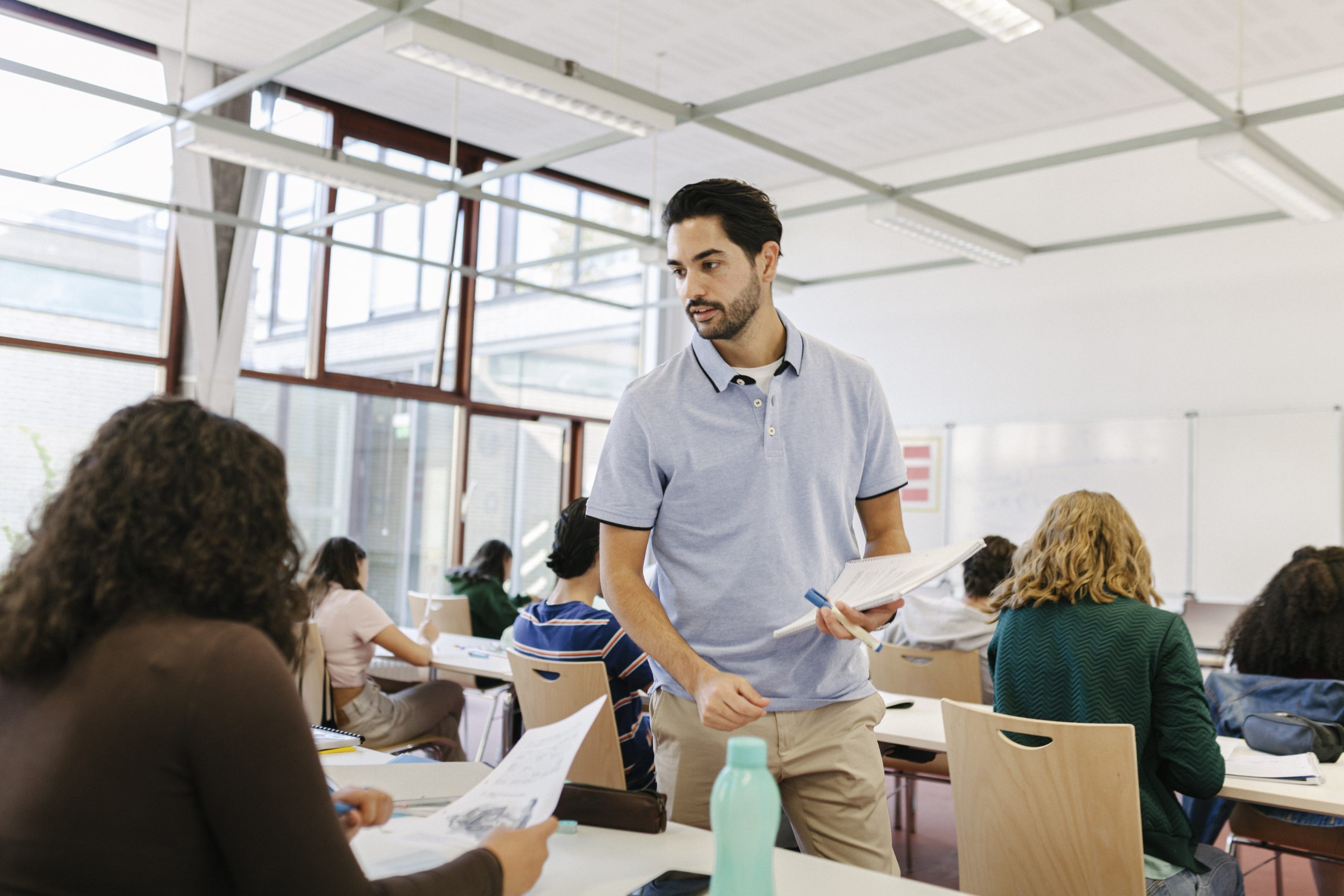 Leerkracht in de klas, papieren uitdelen, secundair onderwijs
